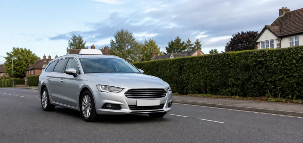 Silver estate taxi on a quiet UK suburban road