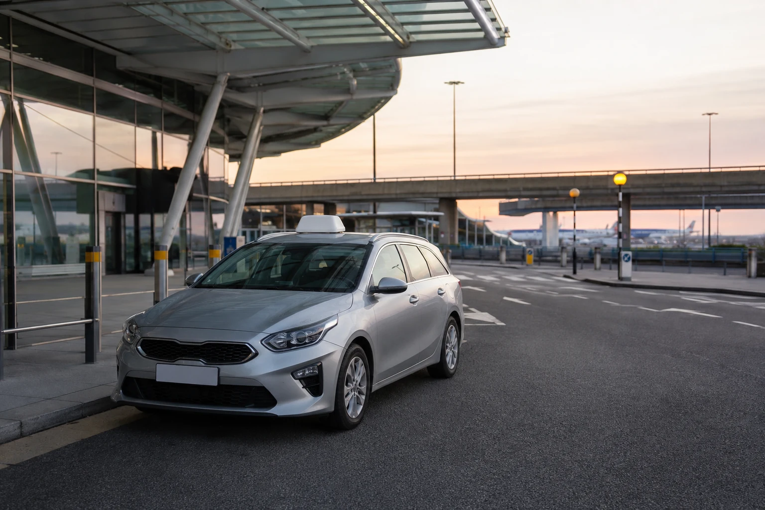 Silver estate taxi at a quiet airport drop-off kerb.